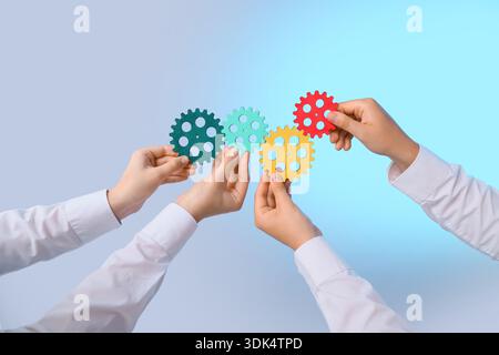 Female hands with colorful gears on light background Stock Photo