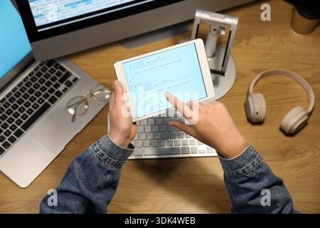 Programmer's hands pointing at modern tablet computer on wooden background Stock Photo