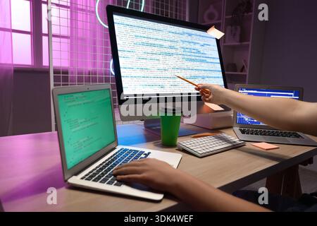 Male programmer working with modern laptop and pointing at computer in office, closeup Stock Photo