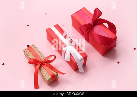 Set of gift boxes and heart-shaped sequins for Valentine's Day celebration on pink background Stock Photo