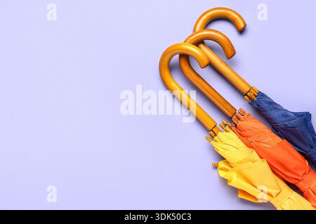 Different stylish umbrellas on lilac background Stock Photo