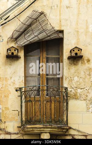 Weathered Balcony Door With Rustic Iron Railing And Birdhouses On Cracked Stone Wall Facade Exterior Stock Photo