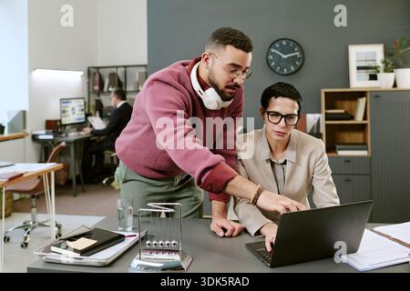 Young Adult Middle Eastern Man Assisting Middle Aged Woman Working Stock Photo