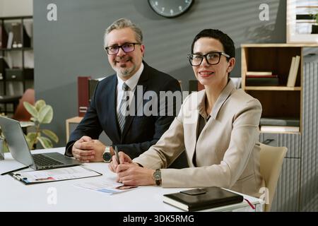 Middle Aged Man and Woman Collaborating in Modern Office Setting Stock Photo