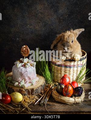 Playful rabbit checks intricately decorated cakes and eggs outdoors Stock Photo