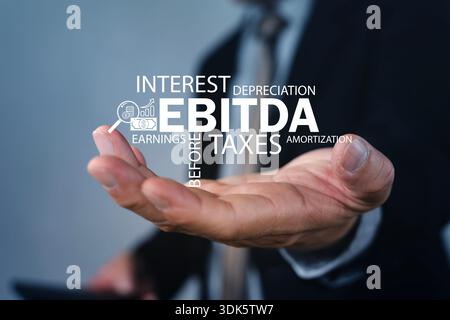 Businessman holding virtual EBITDA word cloud with earnings, interest, taxes, depreciation and amortization. Concept for corporate profitability, valu Stock Photo
