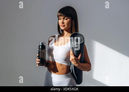 Eyes are closed, sunlight. Young sportive woman is in the studio. Stock Photo