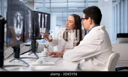 Doctor And Technician Analyze X-ray Imaging On Computer Before Surgery. Diverse Team Stock Photo
