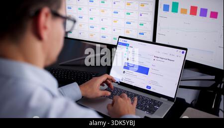 Hispanic Man Utilizing Technology To Track Business Metrics On Multiple Screens. Stock Photo
