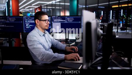 Latin Engineer Develops Code On Desktop Computer In Office Setting. Stock Photo