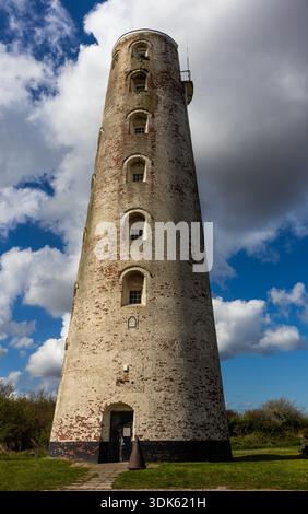 Leasowe Lighthouse weathered brick tower against a bright blue sky with white clouds Stock Photo