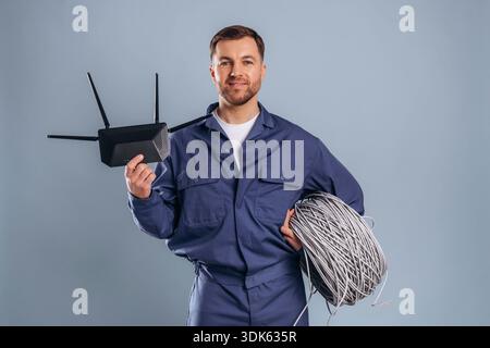 Modern wi-fi router and internet cables. Handsome man is against background. Stock Photo