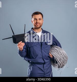 Modern wi-fi router and internet cables. Handsome man is against background. Stock Photo