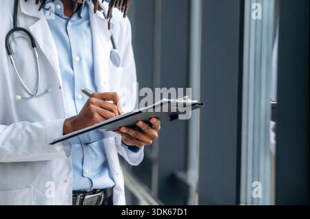 Writing the information into notepad. Close up view of doctor in coat indoors. Stock Photo