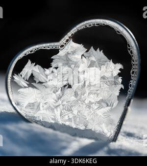 Frozen soap bubble in heart shaped cookie cutter in snow. Stock Photo