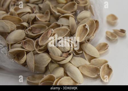 Pistachio shells collected in transparent plastic bag on white background Stock Photo
