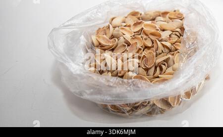 Pistachio shells collected in transparent plastic bag on white background Stock Photo