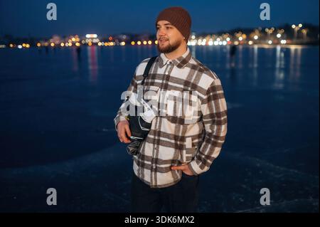 Standing and looking far away. A man is on the ice with his skates in winter. Stock Photo