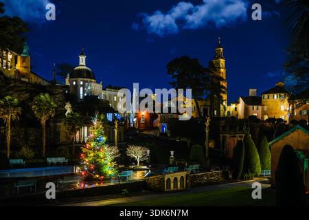 Portmeirion village twinkles with Christmas lights and a sparkling tree in the foreground gardens, illuminating the Pantheon Dome and Campanile tower Stock Photo