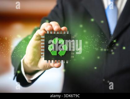 A businessman holds a computer microchip with a recycling symbol in his hand. Recycling of electronic waste. Extraction of valuable metals. Preventing Stock Photo