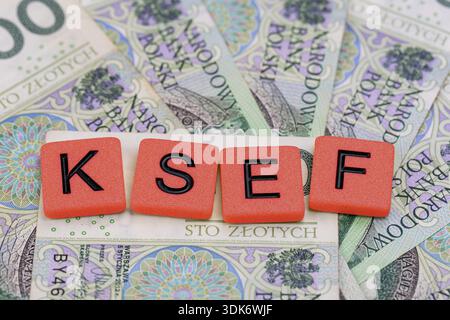 Blocks with the abbreviation KSEF, standing for National E-invoice System, are placed against a background of loosely spread Polish 100 PLN banknotes. Stock Photo
