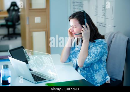 Professional woman interacts with agentic AI hologram and whiteboard. Innovation, future of work, and digital transformation concept. Real people. Stock Photo