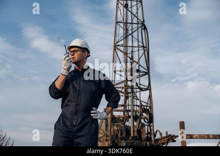 Talking by using walkie talkie. Construction worker is near boring drilling machine. Stock Photo