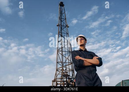 Front view, posing and standing with arms crossed. Construction worker is near boring drilling machine. Stock Photo