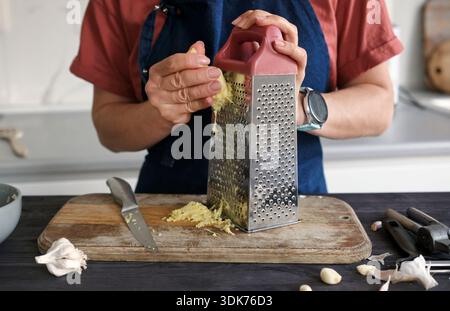 Woman Grating Ginger In The Kitchen At Home Stock Photo