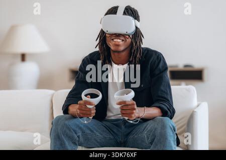 Black man in virtual reality glasses at home. Stock Photo