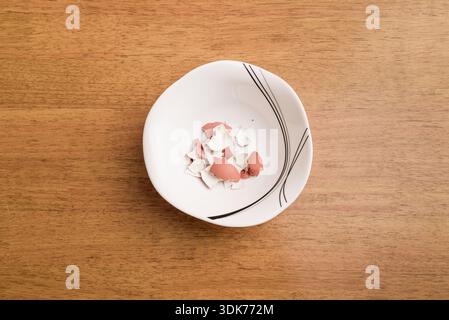 Peeled domestic chicken eggshells on a white plate. Top view. Stock Photo