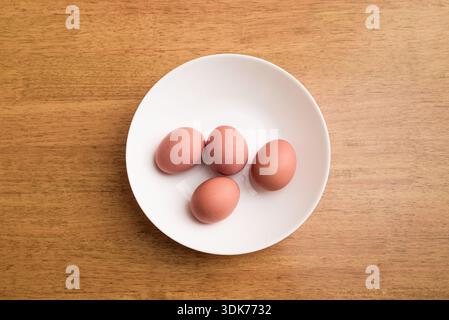 Four Domestic chicken eggs on a white plate. Top view. Stock Photo