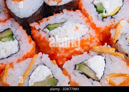 closeup sushi rolls with creamy filling, cucumber and salmon accents, crunchy roe texture, tabletop mood for restaurant menu and food blogger tasting Stock Photo