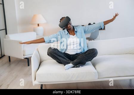Playing game of flying, in VR glasses. Woman is at home in domestic room. Stock Photo