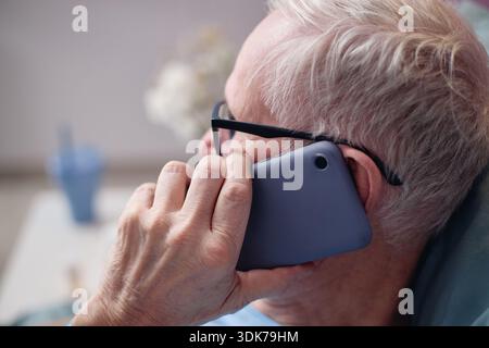 Senior Man Talking on Smartphone While Resting at Vascular Center Stock Photo