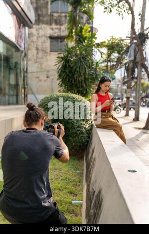 Photographer shooting model during urban street photoshoot Stock Photo