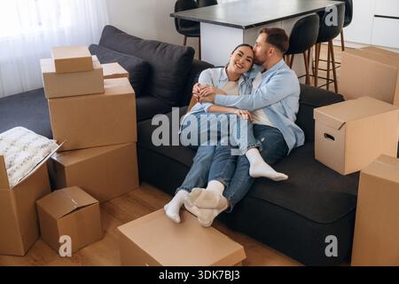 Black sofa, sitting and relaxing. Happy couple moved into new house. Stock Photo