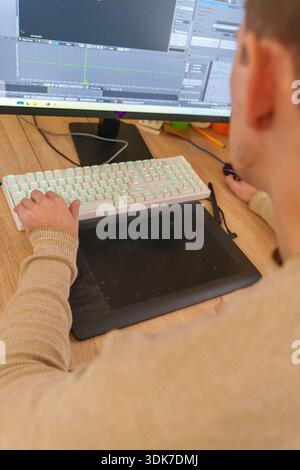 Person working on 3D animation at desk with graphics tablet and mechanical keyboard Stock Photo
