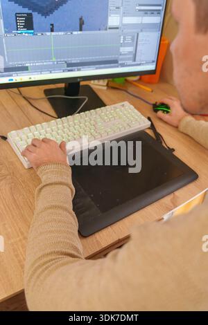 Person working on 3D animation at desk with graphics tablet and mechanical keyboard Stock Photo