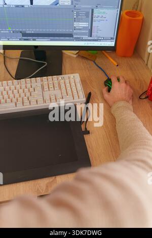 Person working on 3D animation at desk with graphics tablet and mechanical keyboard Stock Photo
