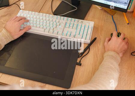 Person working on 3D animation at desk with graphics tablet and mechanical keyboard Stock Photo