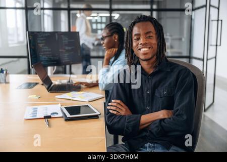 Positive black man is sitting. Business people are working in the office. Stock Photo