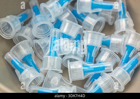 Close-up view of many used medical syringe needles and blue plastic caps. Clinical waste and insulin injection equipment collection for healthcare Stock Photo