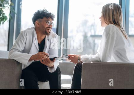Sitting and talking. Man and woman are indoors in modern building. Stock Photo