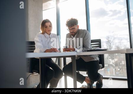 Office workers are on the project. Man and woman are indoors in modern building. Stock Photo