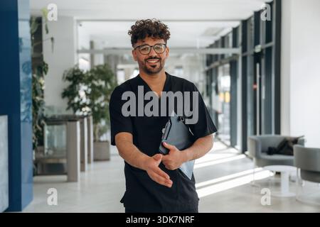 Nice to see you, giving hand to shake. Male doctor is indoors in the modern building. Stock Photo