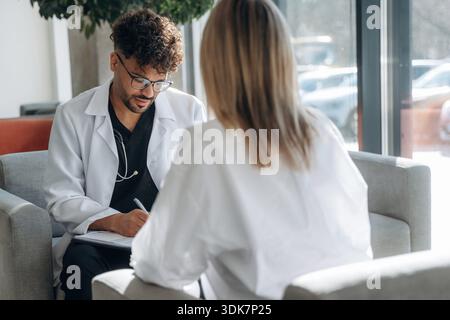 Consultation with doctor. Man and woman are indoors in modern building. Stock Photo