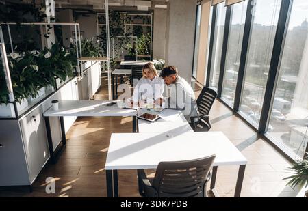 Cooperation, working on project. Man and woman are indoors in modern building. Stock Photo