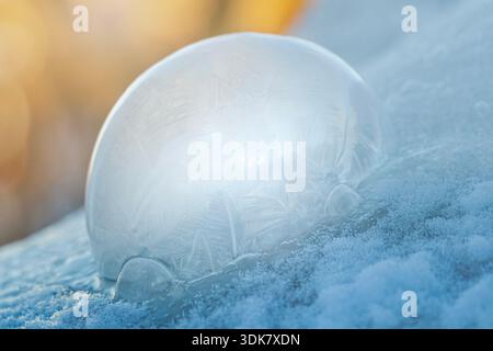 Frozen Soap Bubble in the Snow with Warm Sunlight from Behind Stock Photo