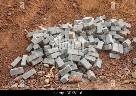 pile of grey concrete paving blocks on brown earth and gravel surface, rectangular stone bricks with rough texture, landscaping and urban development Stock Photo